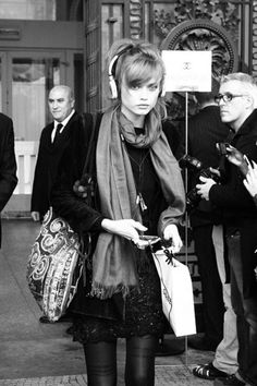 a black and white photo of a woman with headphones in her ears walking down the street