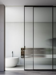 a bathtub sitting next to a glass wall in a bathroom