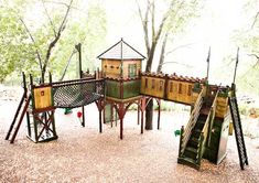 an outdoor play area with several wooden structures and stairs, including a tree house in the background