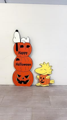 two wooden pumpkins sitting next to each other on top of a tile floor in front of a white wall