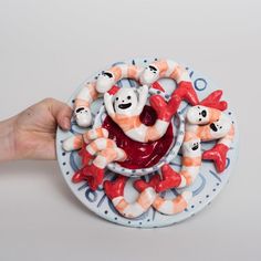 a hand is holding a plate with candy canes in the shape of clowns