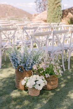 two baskets filled with flowers sitting next to each other on top of a grass covered field