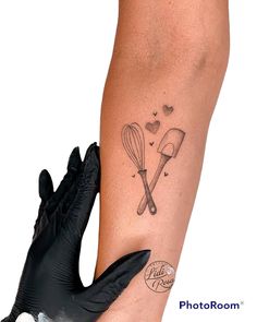 a woman with a tattoo on her leg holding a black glove and cooking utensils