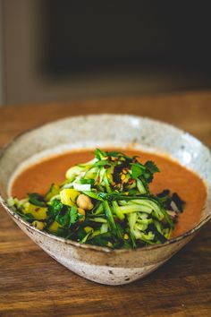 a bowl filled with vegetables on top of a wooden table