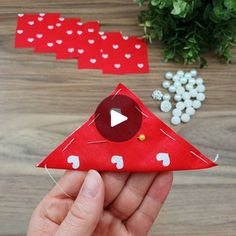 a hand holding a red paper bird with white polka dots