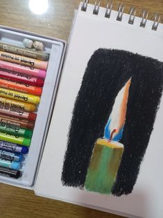 a drawing of a lit candle with crayons next to it on a table