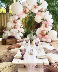 a table set up for a party with pink and white balloons