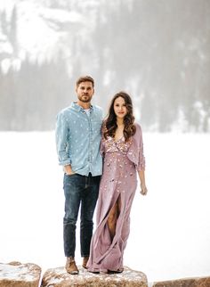 a man and woman standing next to each other on top of a snow covered field