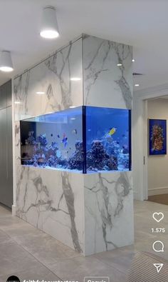 a fish tank in the middle of a room with marble walls and flooring, along with an aquarium