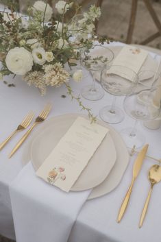 the table is set with white flowers and silverware