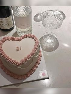 a heart shaped cake sitting on top of a table next to two wine glasses and a bottle