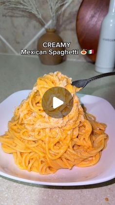 a white plate topped with pasta and sauce next to a bottle of creamy mexican spagettti