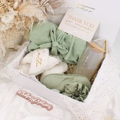 an open box with clothes inside on top of a white sheeted bed next to flowers