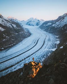 a man standing on top of a snow covered mountain next to a glacier filled with lots of ice