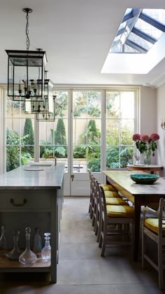 a dining room table and chairs in front of a large window with lots of windows