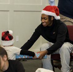 a man in a santa hat handing out a present to a child