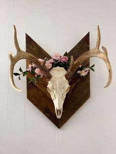 a deer skull with flowers on it mounted to the wall