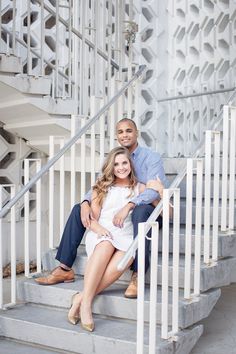 a man and woman sitting on the steps of a white building with their arms around each other