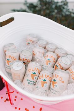 a bucket filled with lots of drinks on top of a pink table covered in confetti