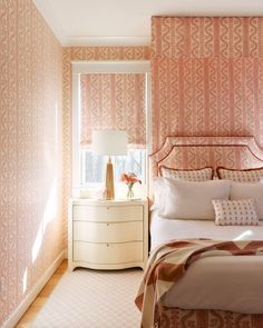 a bedroom with pink wallpaper and white bedding in front of a large window