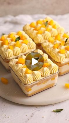 three desserts on a white plate with orange slices around the edges and an olive slice in the middle