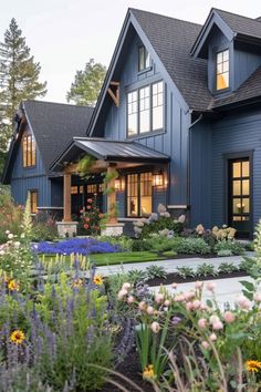 a large blue house with lots of flowers in the front yard and landscaping around it