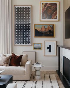 a living room with pictures on the wall and a couch in front of a fire place