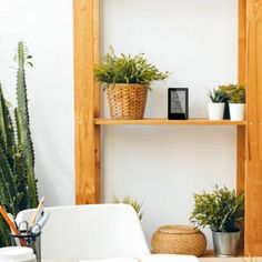 plants and books are sitting on shelves in the corner of a room with white walls