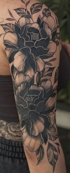 a woman's arm with black and white flowers on the back of her shoulder