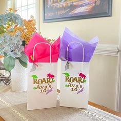 two paper bags sitting on top of a table next to a vase filled with flowers