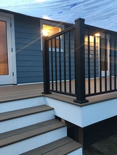 a deck with steps and railings next to a blue house under a tarp