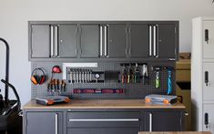 a garage with lots of tools hanging on the wall and cabinets in front of it