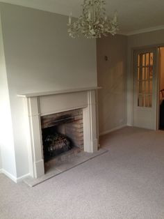 an empty living room with a fireplace and chandelier