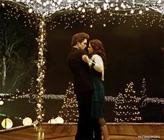 a man and woman dancing in front of christmas lights