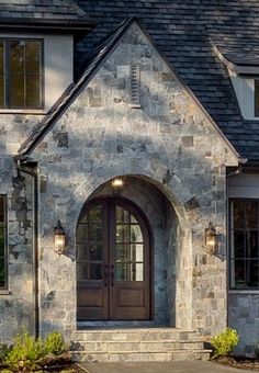 a stone house with two doors and windows on the front door is shown in this image