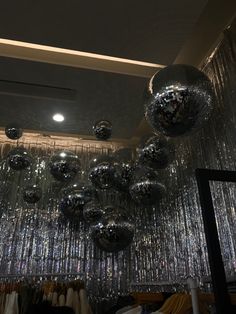 shiny disco balls hanging from the ceiling in a closet with clothes on hangers below