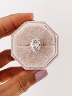 a person holding a ring with a diamond in it's center, on a white background