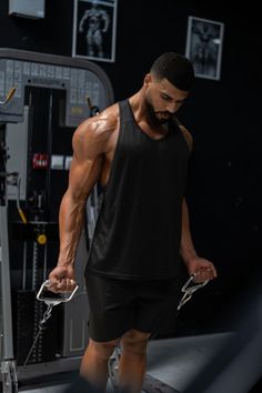 a man in black shirt and shorts standing on a treadmill with his hands behind his back