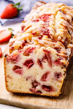 a loaf of strawberry pound cake sitting on top of a cutting board next to sliced strawberries