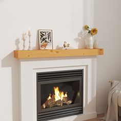 a fire place in a living room with candles and pictures on the mantel above it