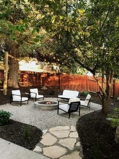 an outdoor fire pit surrounded by chairs and trees