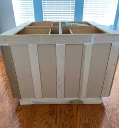 a wooden planter sitting on top of a hard wood floor next to a window