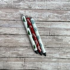 two christmas themed pens sitting on top of a wooden table