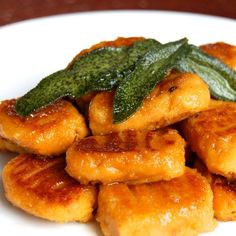 a white plate topped with fried food and green leafy garnish on top of it