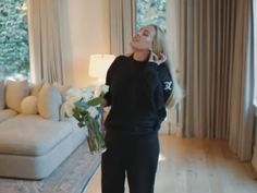 a woman standing in a living room holding flowers