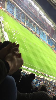 people are sitting in the stands at a soccer game, and one person is holding their hand up