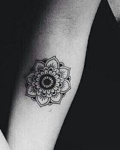 a black and white photo of a woman's arm with a flower tattoo on it