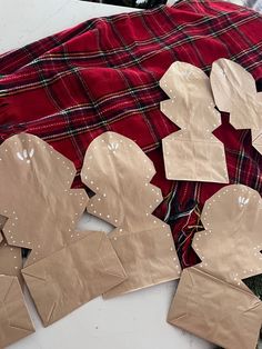 several pieces of paper are cut out and placed on a table with plaid fabric behind them