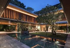 an indoor swimming pool in the middle of a large house with trees and lights around it