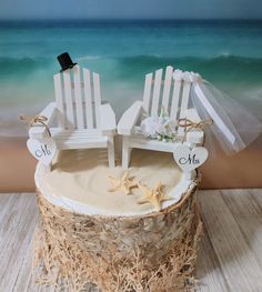 two white beach chairs sitting on top of a wooden stump next to the ocean with starfish